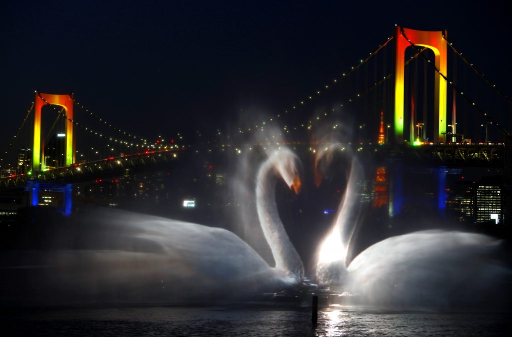 With the backdrop of illuminated Rainbow Bridge and Tokyo skyline, an image of swans appears during Odaiba water illumination show in Tokyo, Japan, Monday, Dec. 21, 2009. The 15-minute slide show depicting the birth of the Earth, projected on a fan-shaped water screen created by a fountain set along a beach at the Tokyo Bay area, will be performed four times a day after dark until Jan. 11, 2010. (AP Photo/Shizuo Kambayashi)
