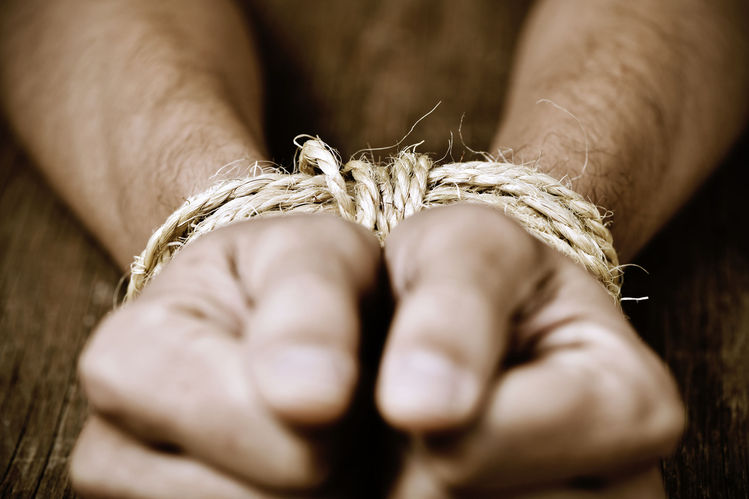 49901113 - closeup of the hands of a young man tied with rope, as a symbol of oppression or repression, with a dramatic effect