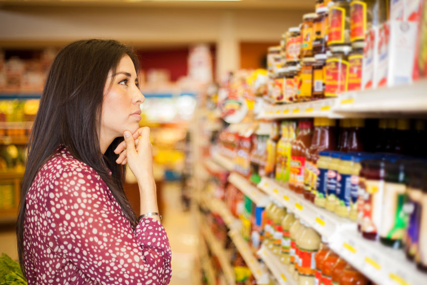 26683537 - beautiful brunette looking at some shelves in a supermarket trying to decide what to buy