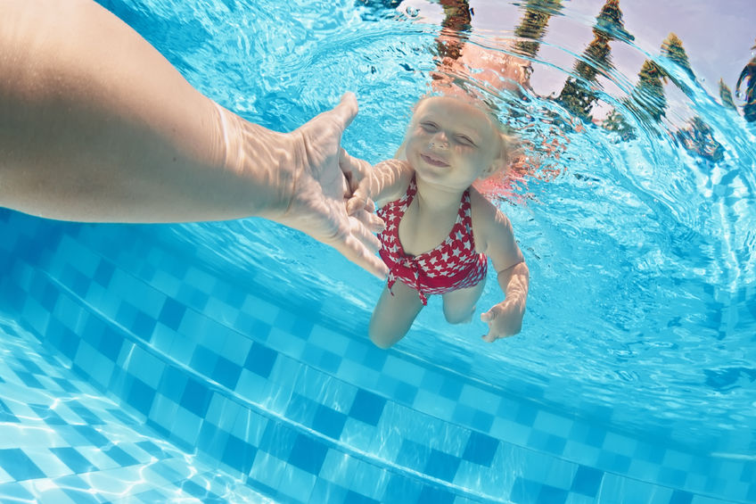 41900312 - joyful baby girl diving underwater with fun and holding parents hand for assistance in swimming pool. healthy active family lifestyle, children water sport activity with mother on summer vacation