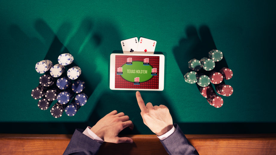 43569275 - poker player's hands with digital tablet, stacks of chips and cards on green table, top view