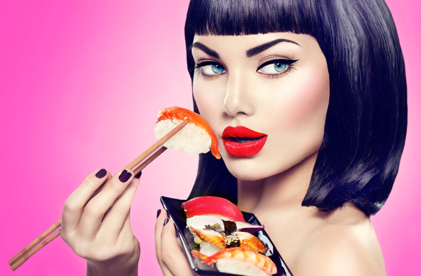 42872725 - beauty model girl eating nigiri sushi with chopsticks