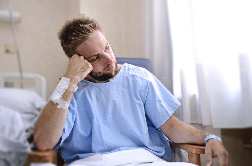 42892280 - young injured man in hospital room sitting alone in pain looking negative and worried for his bad health condition sitting on chair suffering depression on a sad lonely medical background