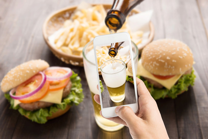 42935139 - using smartphones to take photos beer being poured into glass with gourmet hamburgers