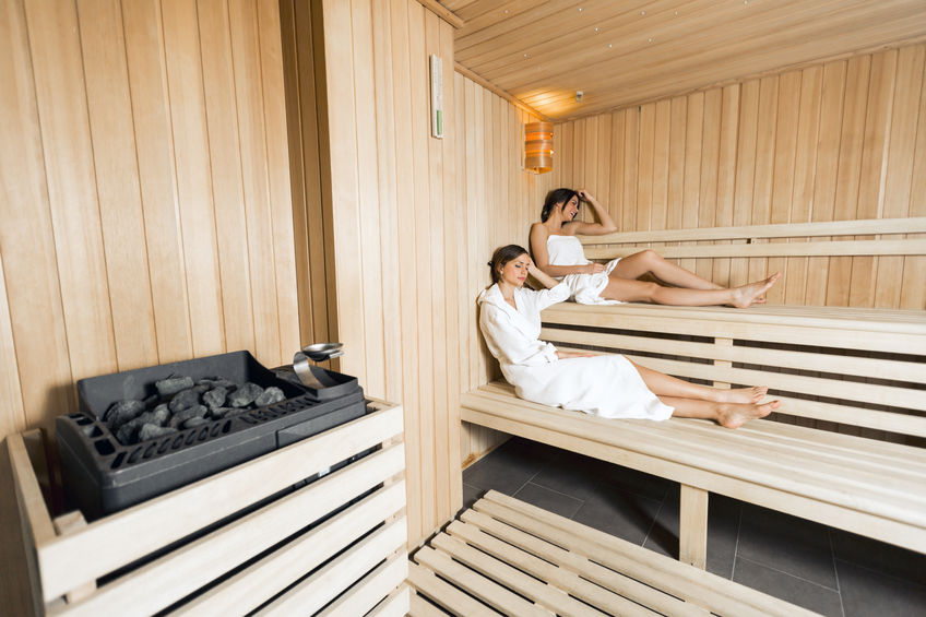 43692420 - sauna heater in a cozy sauna and girls relaxing in the background