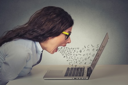 46737925 - angry furious businesswoman working on computer, screaming with alphabet letter coming out of open mouth. negative human emotions, facial expressions, feelings, anger management issues concept