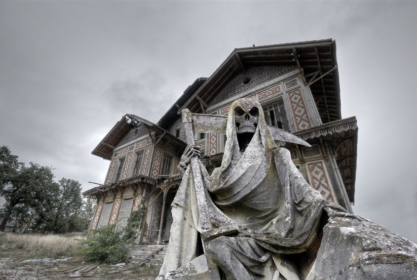 18658220 - haunted house abandoned and ruined manor with a gream reaper statue in foreground