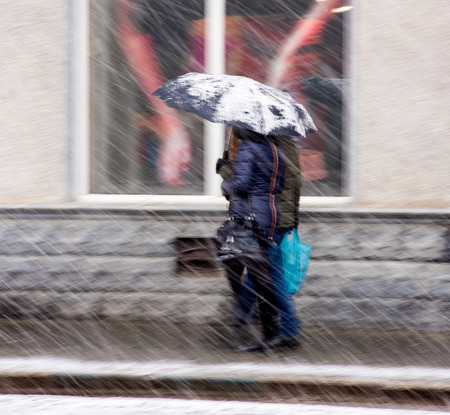 36868470 - people walking down the street in a snowy winter day in motion blur