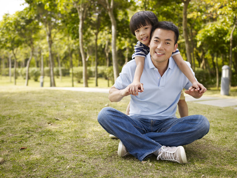 40150490 - asian father and elementary-age son enjoying outdoor activity in park.