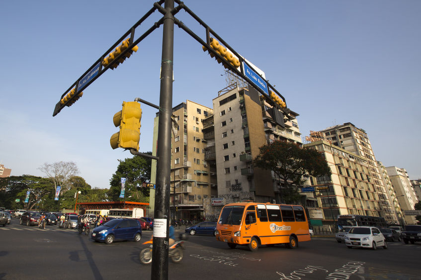 42696638 - caracas, venezuela, april 20: street crossing with small traffic, bus, cars and motos, early in the morning in caracas against a blue sky, venezuela 2015.