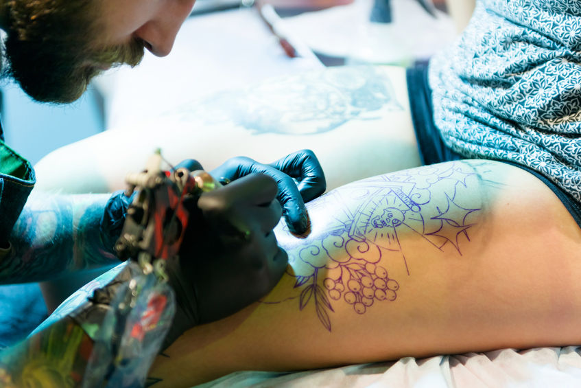 46032445 - minsk, belarus - september 19, 2015: professional tattoo artist doing tattoo on client leg. the 2th international tattoo convention
