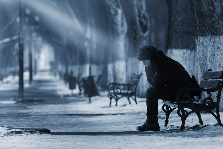46471589 - sad woman sitting on a bench in winter time.