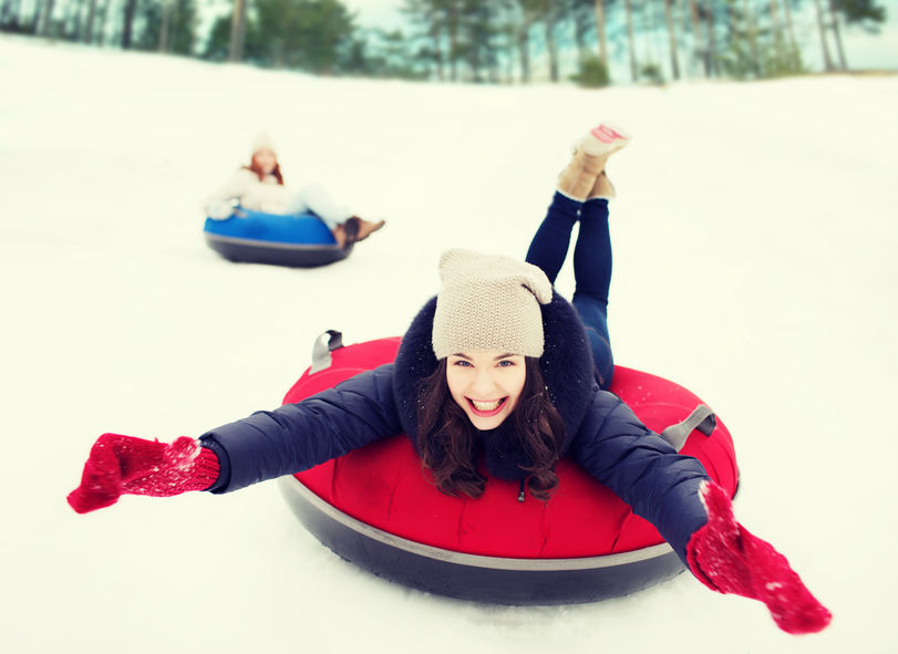 49161517 - winter, leisure, sport, friendship and people concept - group of happy friends sliding down on snow tubes