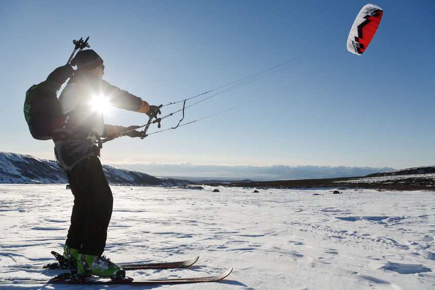 49377900 - kamchatka peninsula, russia - november 22, 2014: snowkiting or kiteboarding - sportsman glides on skis on snow in sunny weather at sunset.
