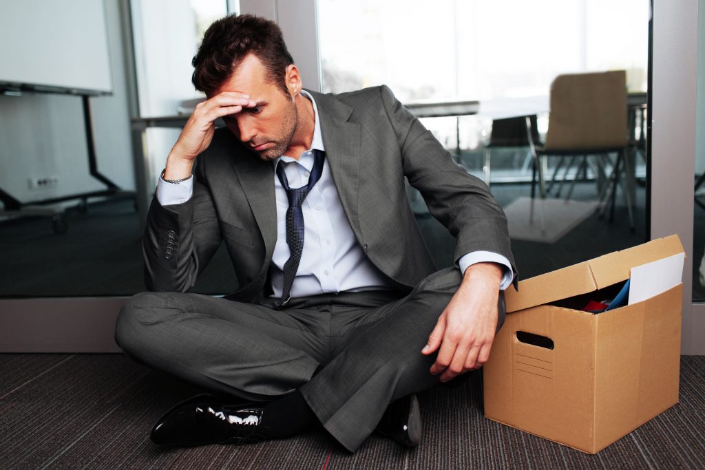 53957480 - sad fired businessman sitting outside meeting room after being dismissed