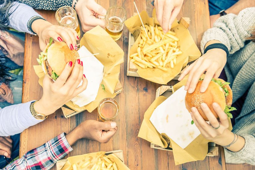 40113568 - group of friends toasting beer glasses and eating at fast food - happy people partying and eating in home garden - young active adults in a picnic area with burgers and drinks