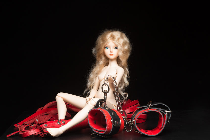 43902456 - concept. doll with different sex toys. whip and handcuffs