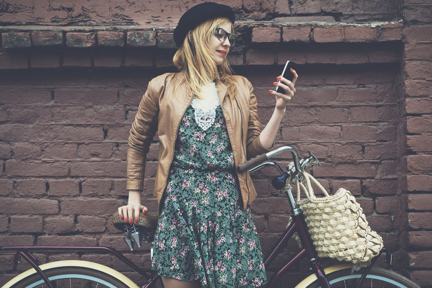 46656418 - city lifestyle stylish hipster girl with bike using a phone texting on smartphone app in a street