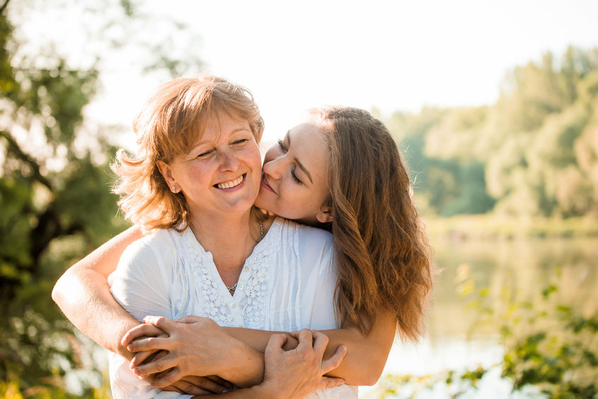 52579542 - mature mother hugging with her teen daughter outdoor in nature on sunny day