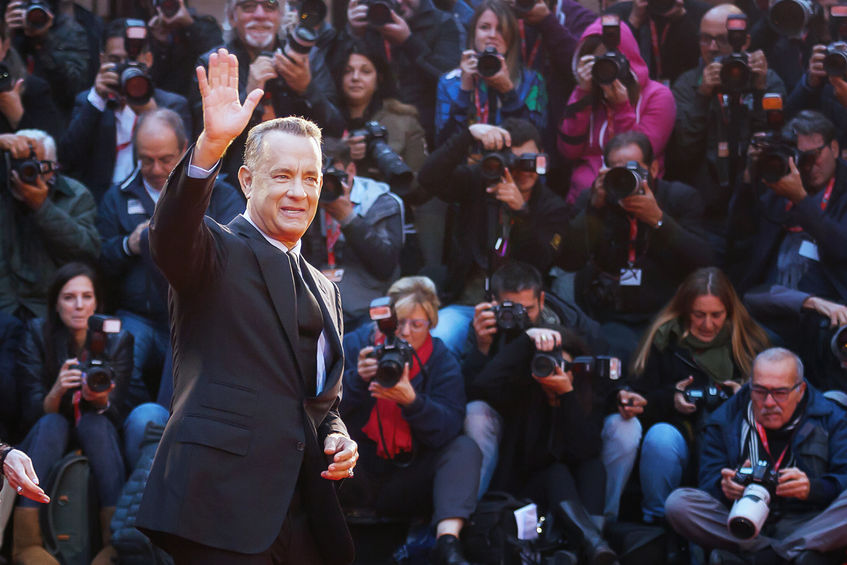 64566835 - rome, italy - october 13, 2016: tom hanks on the red carpet at the 11th film festival in rome, greets the audience.american actor tom hanks on the red carpet at the 11th film festival in rome, hank greets the audience, raising his arm, and behind him a cr