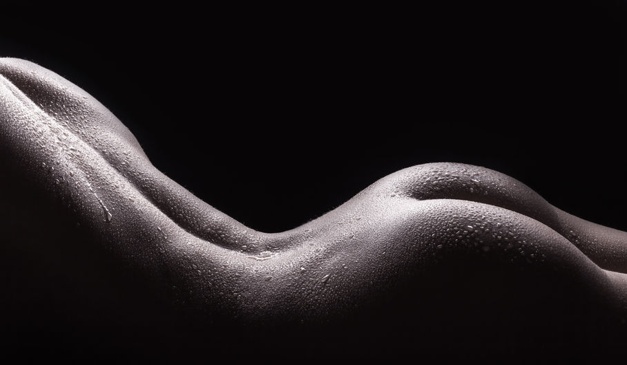 36734424 - beautiful buttocks of a nude young woman with wet body, closeup on dark background
