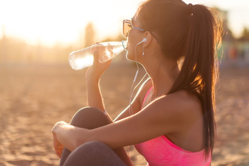 41162100 - beautiful fitness athlete woman drinking water after work out exercising on sunset evening summer in beach outdoor portrait