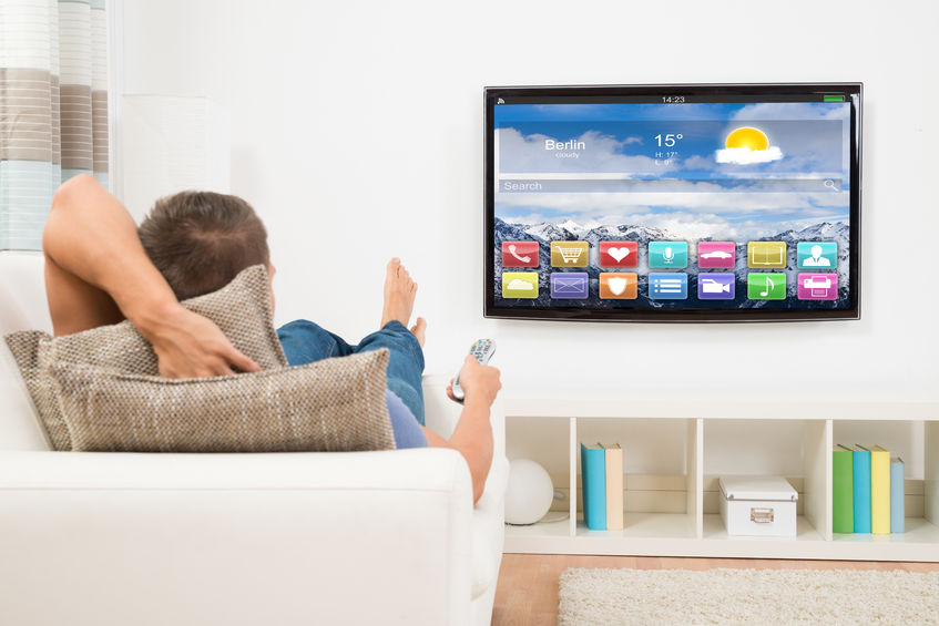 44589454 - young man lying on sofa using remote control in front of television