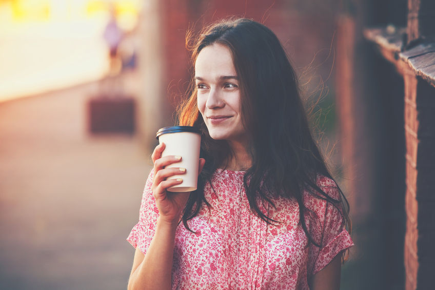 46675110 - smiling pretty girl walking in street with morning coffee