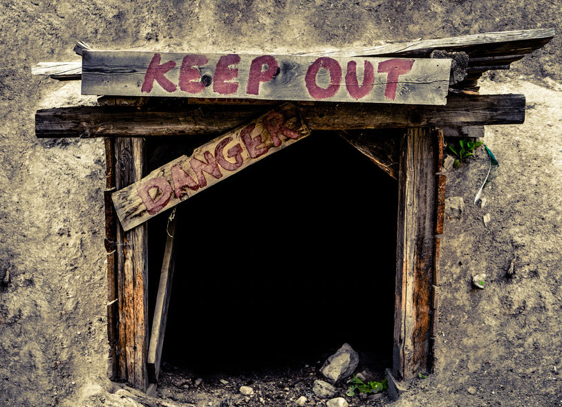 46912153 - conceptual image of a an entrance to an old mine tunnel with keep out and danger signs