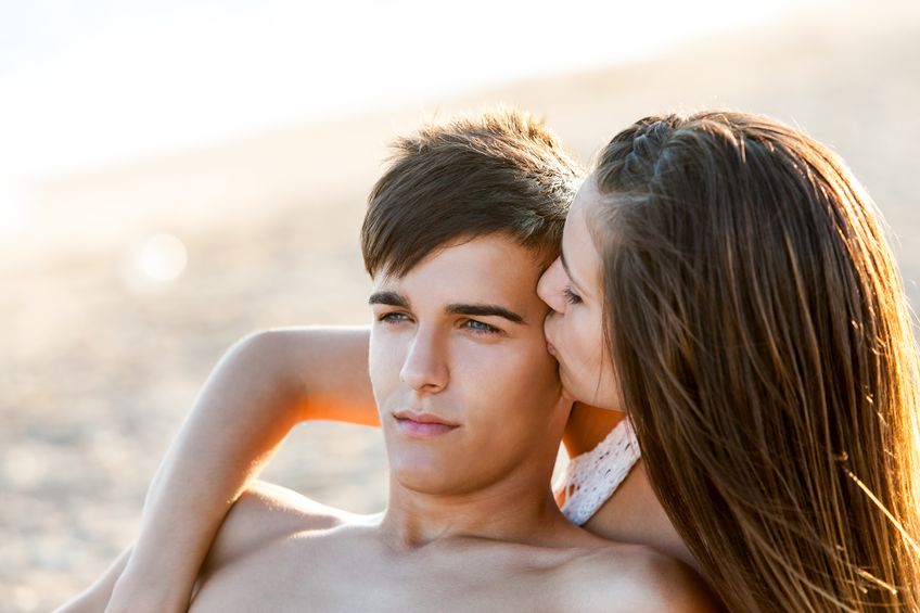 22618103 - teen girl kissing boyfriend on cheek at sunset.