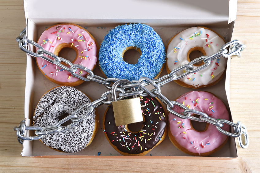 40416435 - box full of tempting delicious donuts wrapped in metal chain and lock in sugar and sweet addiction and diet body and dental care concept