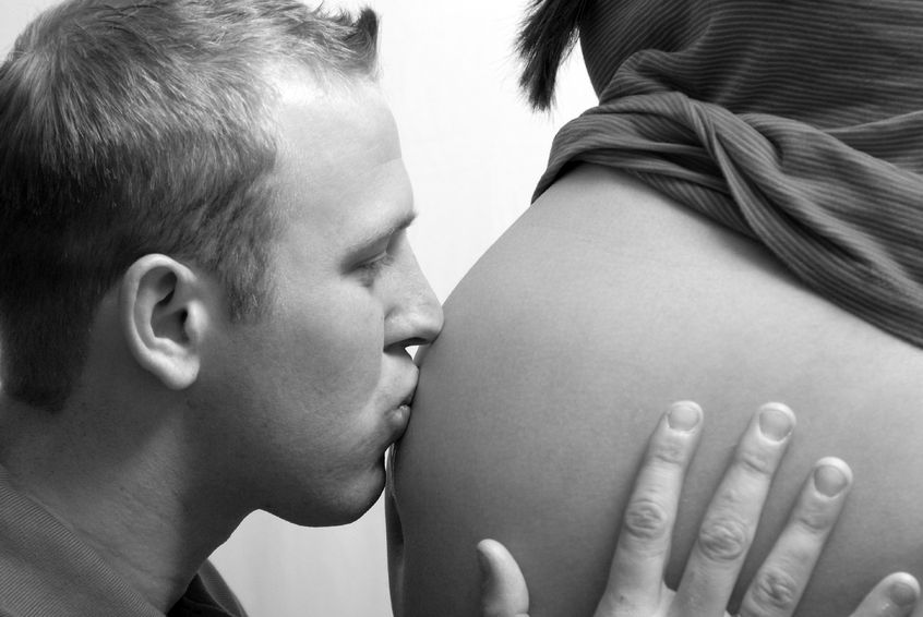 12687186 - a man kissing his unborn childs pregnant belly.
