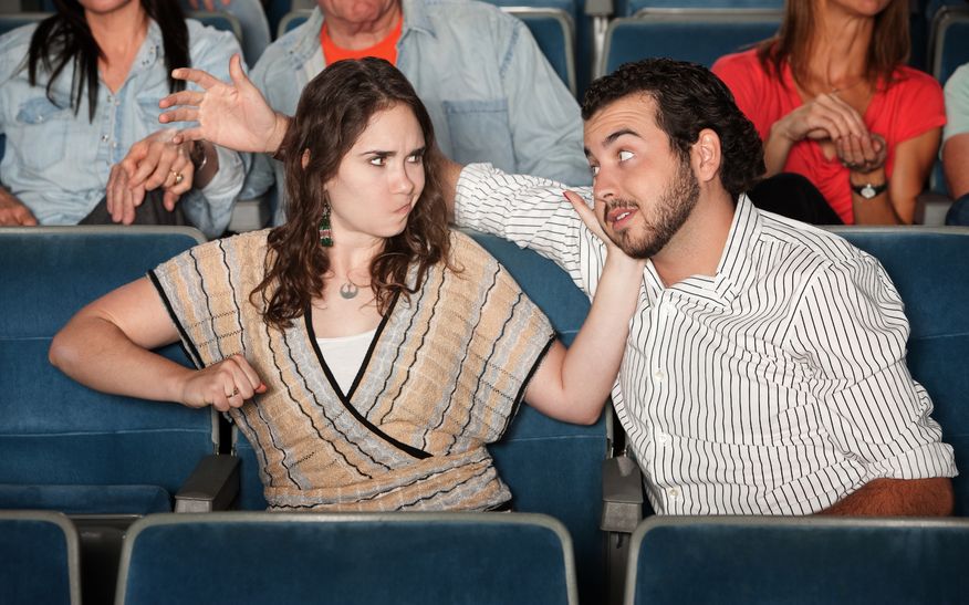 12923562 - irked woman gestures to punch man in theater
