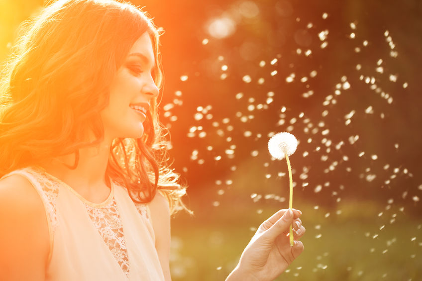 39394923 - young spring fashion woman blowing dandelion in spring garden. springtime. trendy girl at sunset in spring landscape background. allergic to pollen of flowers. spring allergy