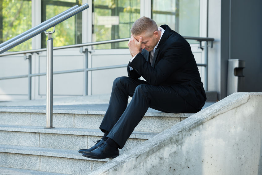48131895 - portrait of a depressed businessman sitting on stairs