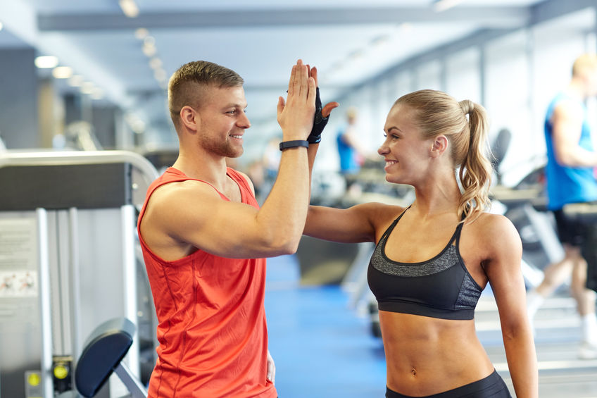 54750894 - sport, fitness, lifestyle, gesture and people concept - smiling man and woman doing high five in gym