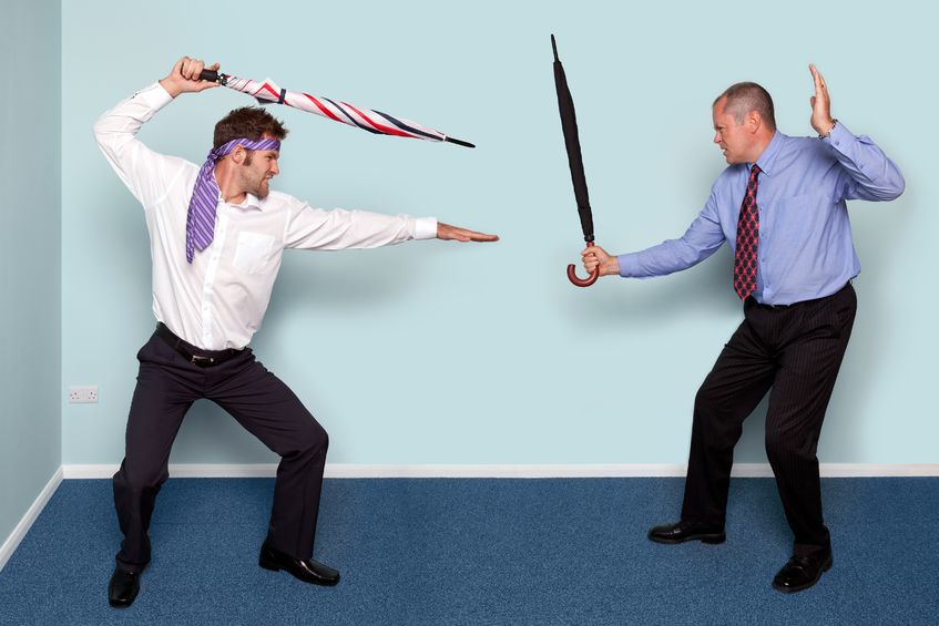 11020158 - photo of two businessmen having a sword fight using umbrellas, good image to convey conflict, rivalry or disagreement.