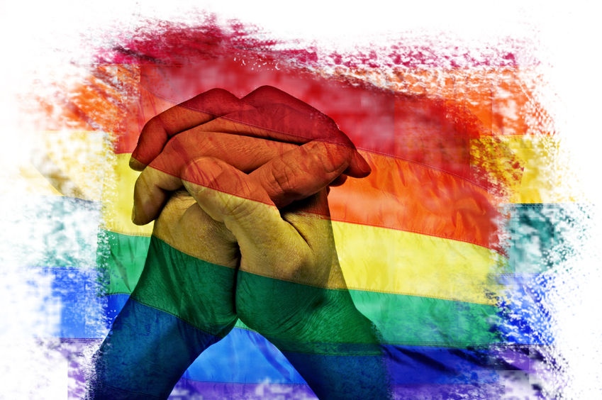 41212650 - multiple exposures of the rainbow flag in different patterns and the clasped hands of a young man