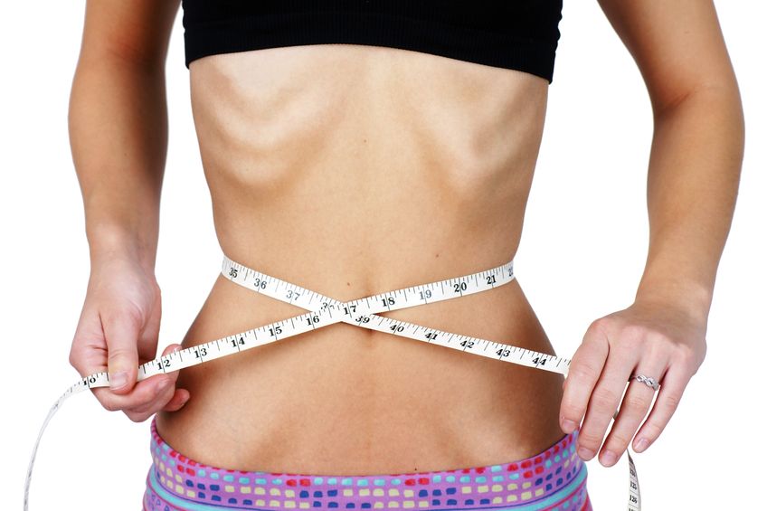 15974280 - anorexic and weight obsessed young woman, measuring her very thin and slim waist, torso with ribs and hip bones clearly showing, perfect for mental health and body dismorphia issues.