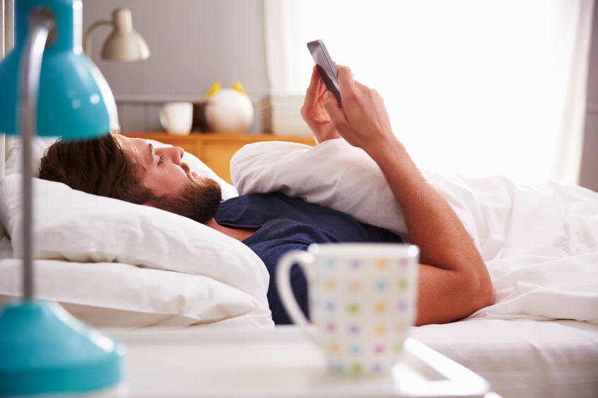 41147093 - man lying in bed checking mobile phone