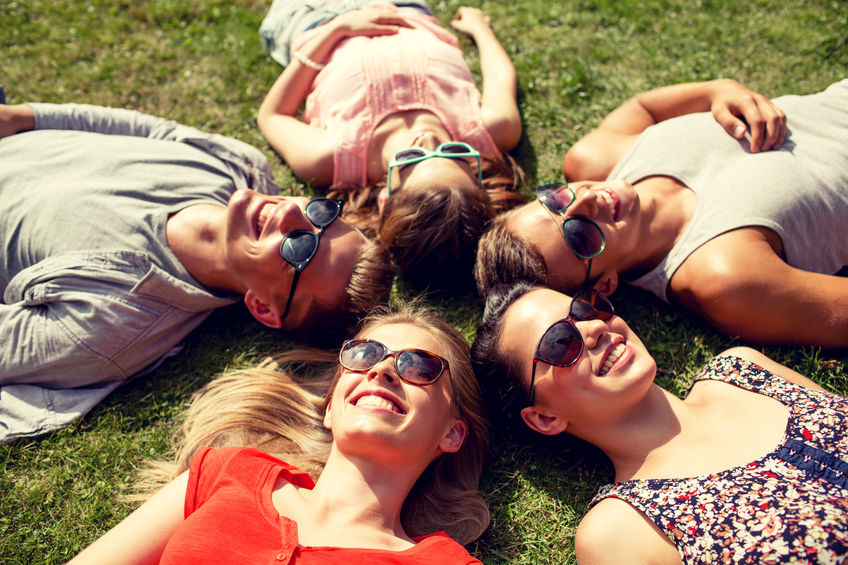 41729173 - friendship, leisure, summer and people concept - group of smiling friends lying on grass in circle outdoors