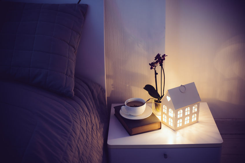 51446479 - cozy evening bedroom interior, cup of tea and a night light on the bedside table. home interior decor with warm light.