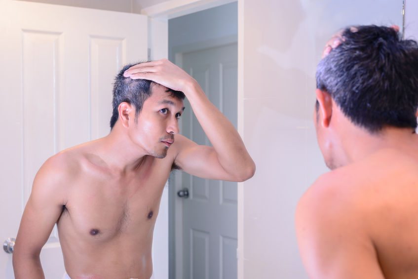 52685428 - man worried about gray hair while looking into a mirror.