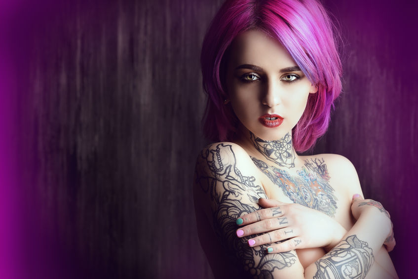 53482023 - beautiful young woman with stylish crimson hair and tattoo on her body posing over dark grunge background. hair coloring. cosmetics, make-up. tattoo.