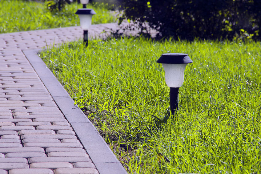 70001539 - garden lighting - lights on the solar battery on a green lawn next to a paved path