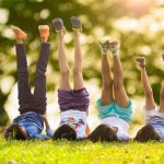 26772943 – group of happy children lying on green grass outdoors in spring park