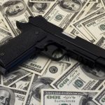42266485 – black and chrome gun pistol and money dollars background filtered