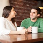 53298688 – cute happy couple enjoying a cup of coffee while on a date at a cafe