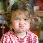 59700972 – funny portrait of adorable baby girl. child makes grimaces face