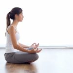 Beautiful young woman doing yoga exercises at home.